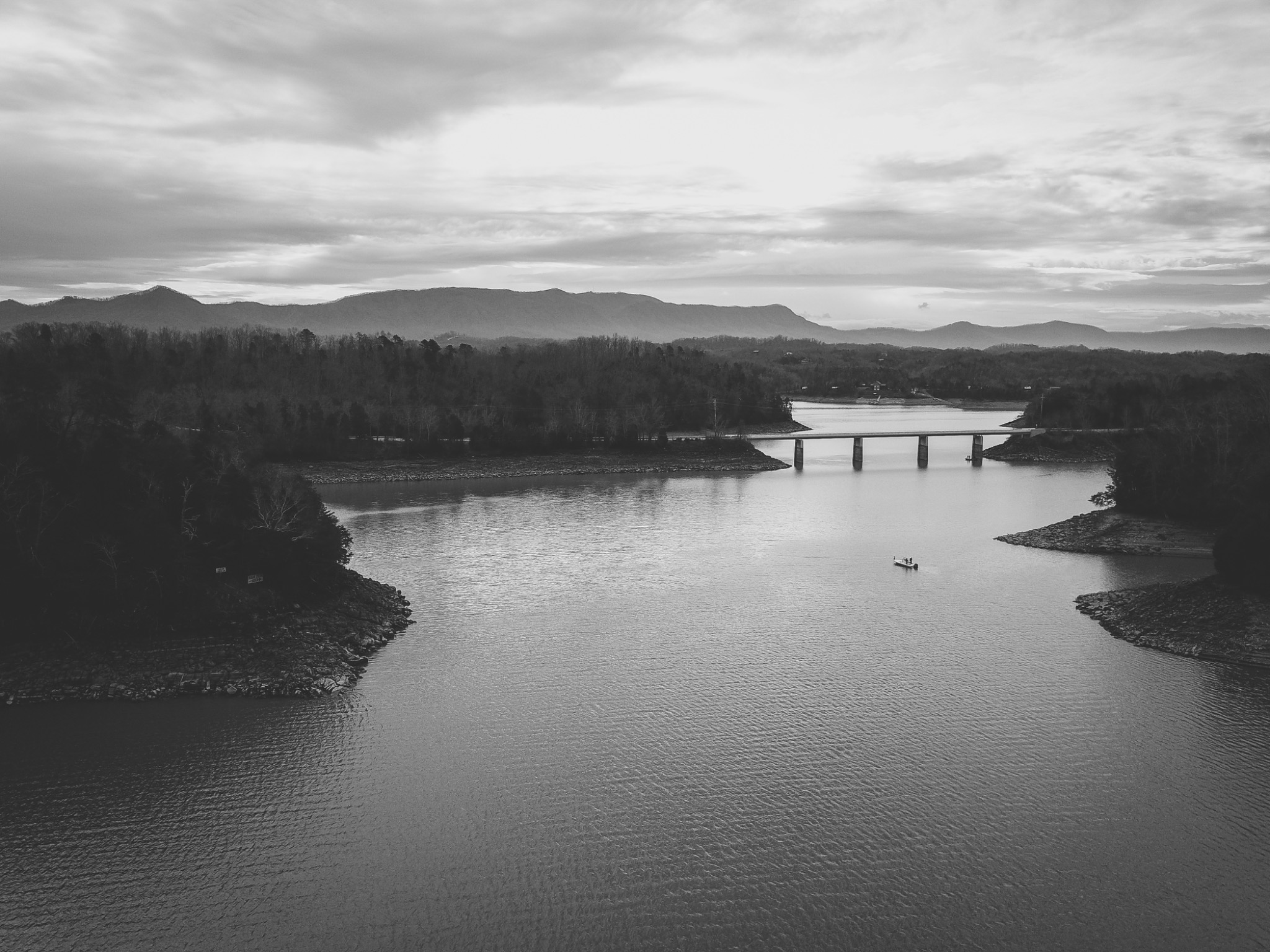 A lone fishing boat on Lake Douglas beneath layered mountains