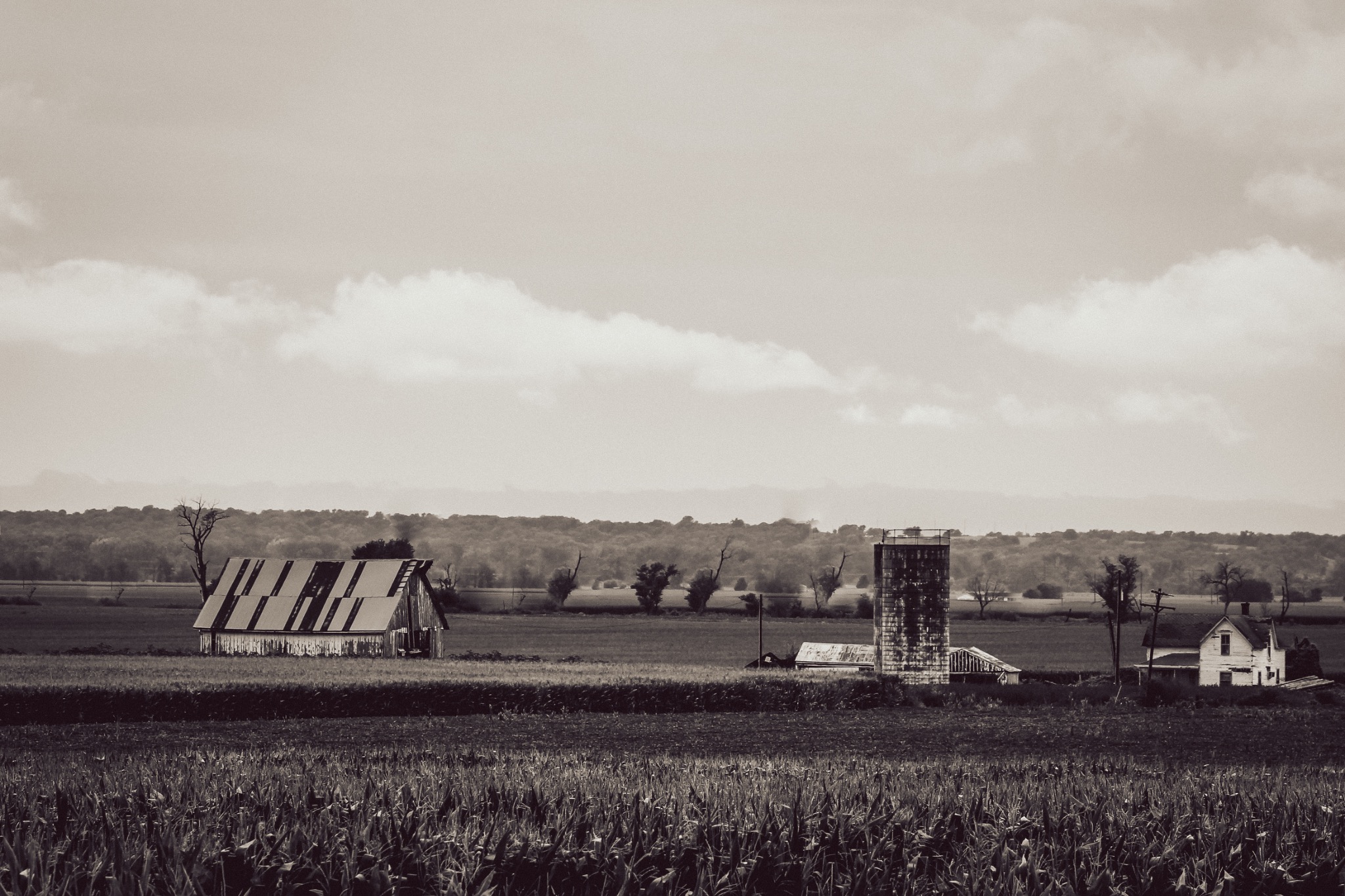 A weathered barn and silo beneath a dramatic rural sky